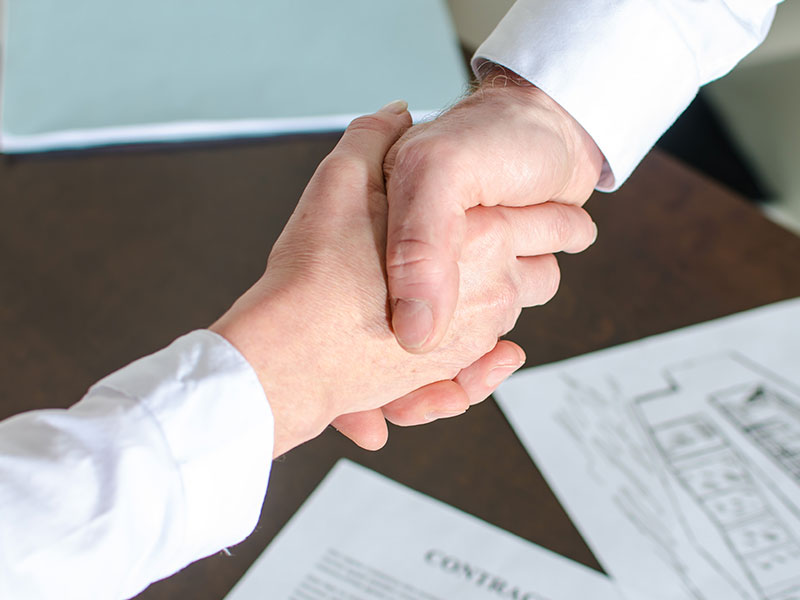 Hand Shake Over House Plans